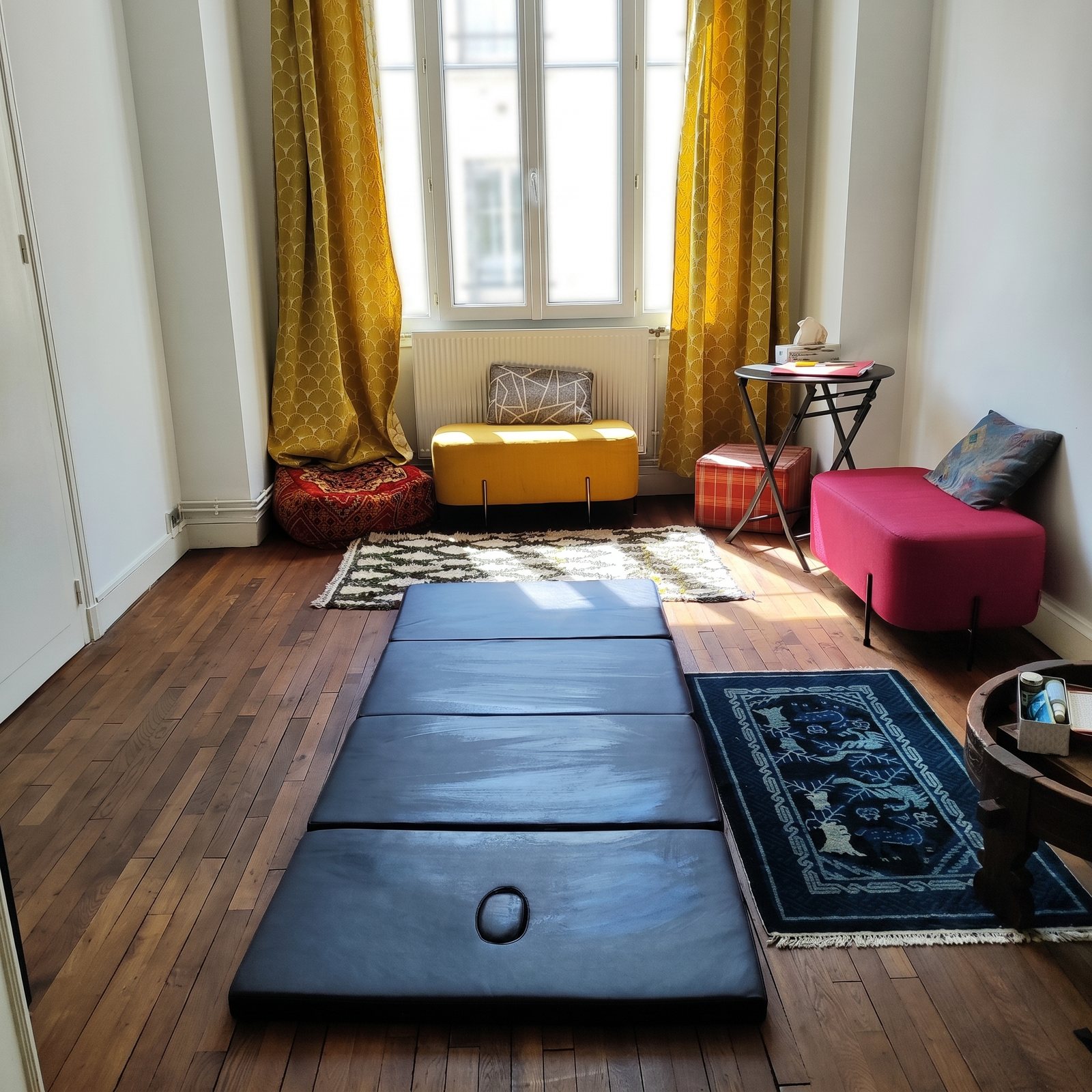 Le cabinet de Cécile : une pièce lumineuse avec un futon au sol, des tapis et des coussins